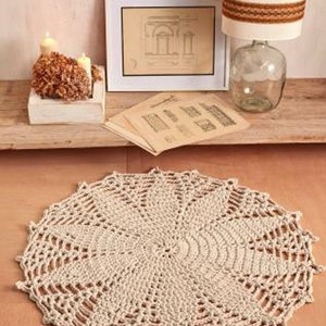May include: A large, round, crocheted rug in a cream color with a delicate, intricate pattern. The rug is made of thick yarn and has a soft, textured surface.