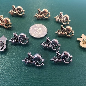 Könnte beinhalten: Sortiment an silbernen und goldenen Knöpfen in Engelform. Die Knöpfe haben einen Durchmesser von etwa 2,5 cm und zeigen ein Cherubim-Design.