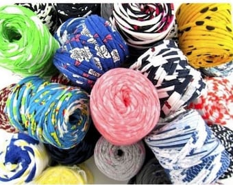May include: A collection of colorful yarn made from recycled fabric scraps. The yarn is in various patterns and colors, including green, blue, pink, yellow, and black.