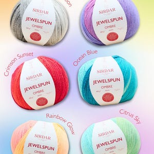 Puede incluir: Seis ovillos de lana Sirdar Jewelspun Ombre Aran en varios colores: Silvery Moon, Violet Dawn, Crimson Sunset, Ocean Blue, Rainbow Glow y Citrus Sky. Cada ovillo tiene una etiqueta blanca con el nombre de la marca y detalles del hilo.