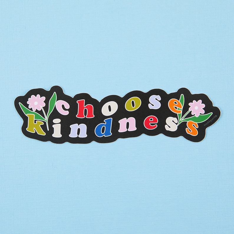 May include: Black sticker with the words "choose kindness" in colorful letters and two pink flowers with green stems on a light blue background.