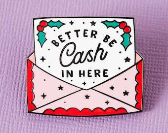 May include: Red and white enamel pin shaped like an envelope with a white paper inside. The paper has a green holly sprig with red berries and the text "Better be cash in here".