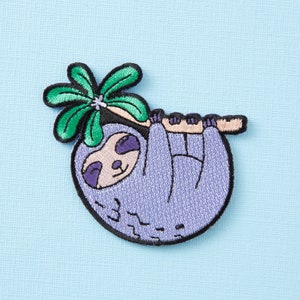 May include: Purple sloth with a green palm tree hanging from a branch, embroidered on a light blue fabric.