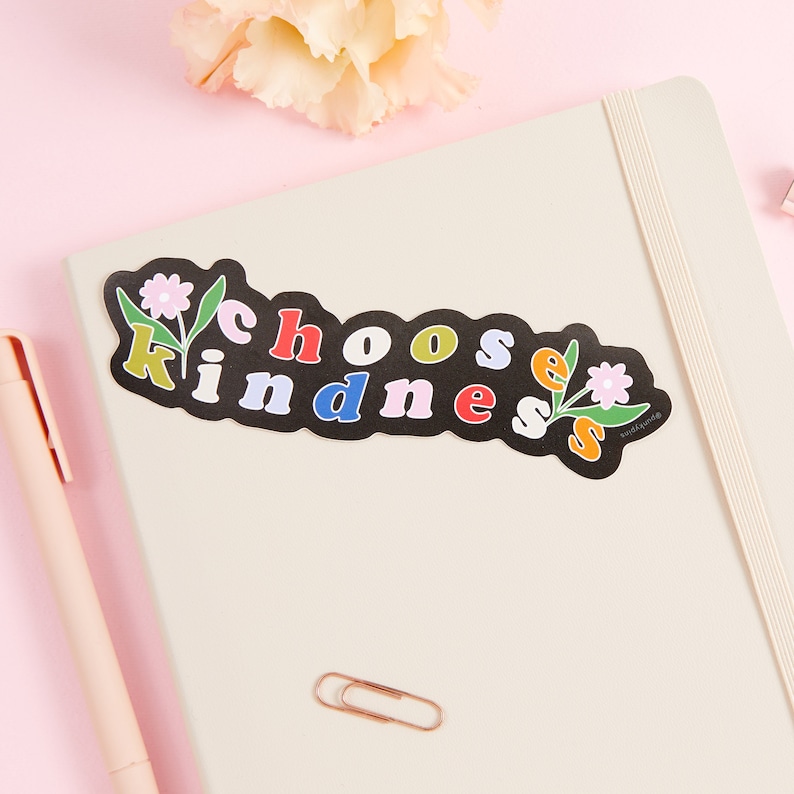 May include: A black sticker with the text "Choose Kindness" in colorful letters. The sticker has a floral design with pink flowers and green leaves.