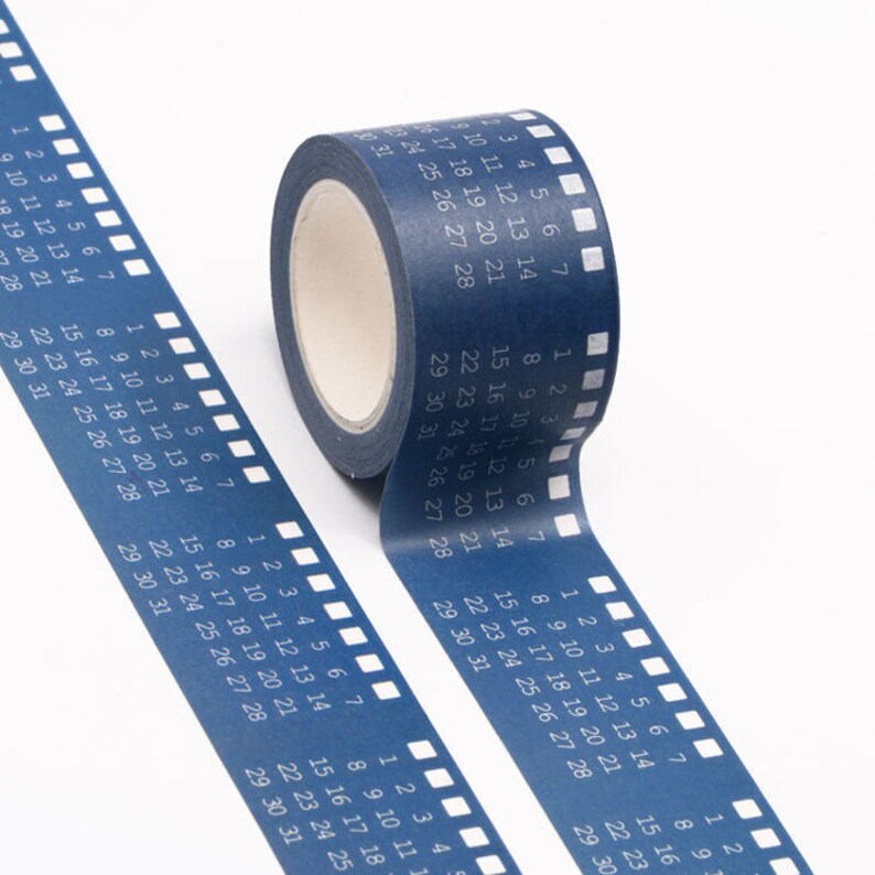May include: A roll of blue washi tape with a calendar design. The tape features white numbers and a film strip pattern.