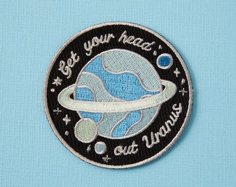 Może przedstawiać: Naszywka haftowana w kolorze czarnym i białym z planetą i tekstem "Get your head out Uranus".