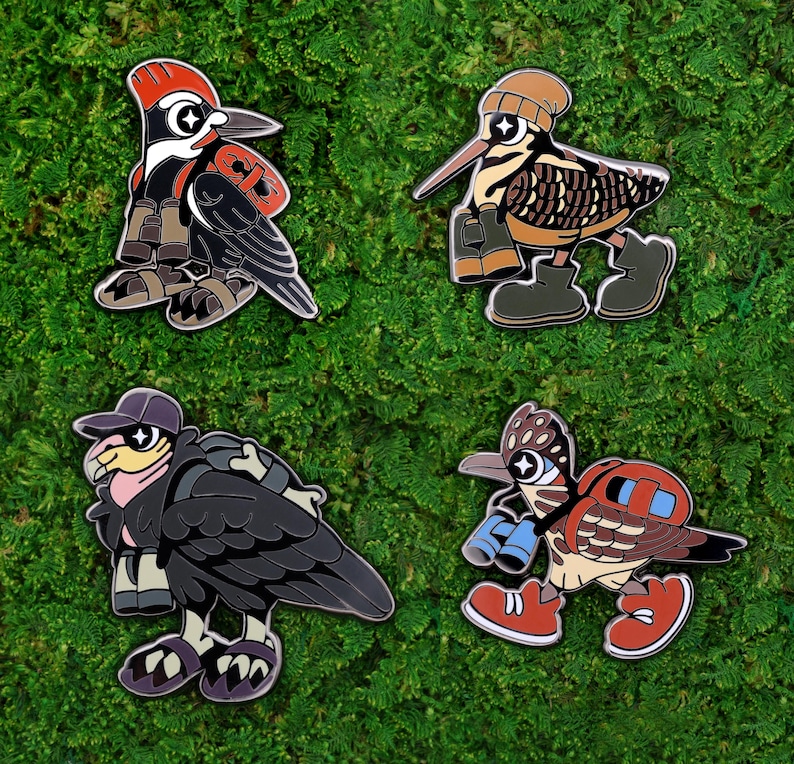 May include: Four enamel pins featuring cartoon birds with unique designs. The birds are depicted with hats, backpacks, and boots, set against a green moss background. The pins showcase a woodpecker, a snipe, a vulture, and a roadrunner.