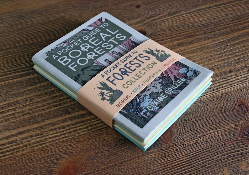 May include: A stack of three softcover books titled A Pocket Guide to Boreal Forests, held together by a peach-colored paper band labeled A Pocket Guide to Forests Collection by Claire Spiller, featuring illustrations of trees and plants.