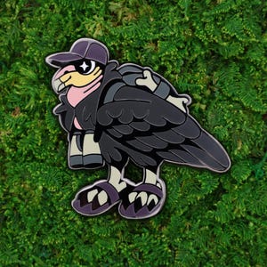 May include: A cartoon-style enamel pin of a vulture wearing a purple baseball cap and sunglasses. The vulture has black feathers, a pink neck, and is wearing a backpack and sandals. The pin is set against a green background.