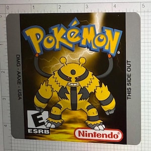 Puede incluir: Un cartucho de videojuego Pokemon amarillo y negro con un Pokemon de tipo eléctrico amarillo y negro en la parte delantera. El cartucho está etiquetado como "Pokemon" y "DMG-AAXE - USA". La clasificación ESRB "E" es visible en la esquina inferior izquierda. El logotipo de Nintendo está en la esquina inferior derecha. El texto "THIS SIDE OUT" está en el lado derecho del cartucho.