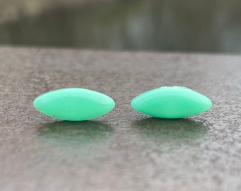 Op de afbeelding: Twee kleine, ovale, lichtgroene oorbellen.