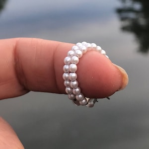 Può includere: Un anello di perle bianche con più file di perle.