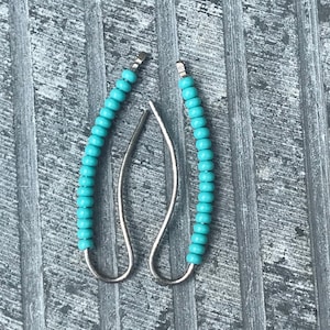 May include: A pair of turquoise beaded earrings with silver wire.