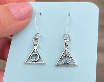 Op de afbeelding: Een paar zilveren oorbellen met een driehoekige hanger met het symbool van de Doodsmerte uit de Harry Potter-serie.