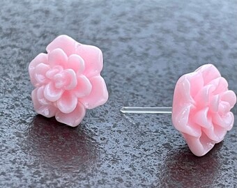 Op de afbeelding: Een paar roze bloem oorknopjes. De oorbellen zijn gemaakt van een glad, glanzend materiaal en hebben een delicaat, vrouwelijk ontwerp.