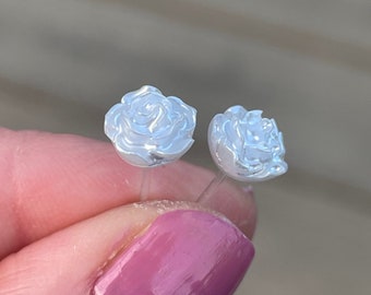 Op de afbeelding: Een paar witte roos oorbel studs. De oorbellen zijn klein en delicaat, met een eenvoudig ontwerp.