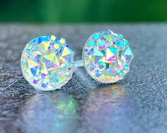 Op de afbeelding: Een paar oorbelletjes met een iriserende kristallen. De oorbelletjes zijn rond en hebben een facetgeslepen ontwerp.