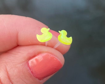Op de afbeelding: Een paar gele rubberen eendjes oorbellen. De oorbellen zijn klein en hebben een eenvoudig ontwerp.