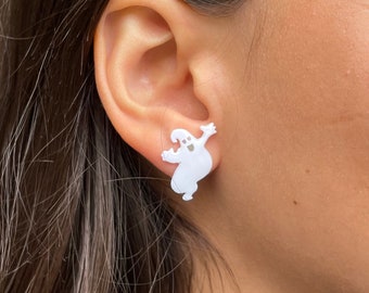 Op de afbeelding: Witte oorbel studs in de vorm van een spook. Het spook is afgebeeld met een glimlachend gezicht en uitgestrekte armen.
