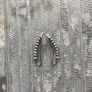 May include: A pair of silver earrings with a row of black beads hanging from each earring.