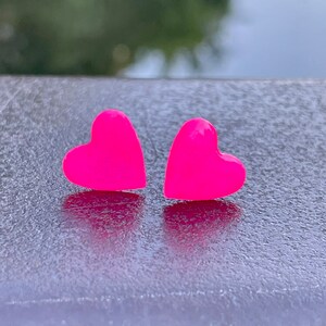 May include: A pair of pink heart-shaped stud earrings.