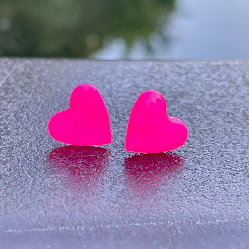 May include: A pair of pink heart-shaped stud earrings.