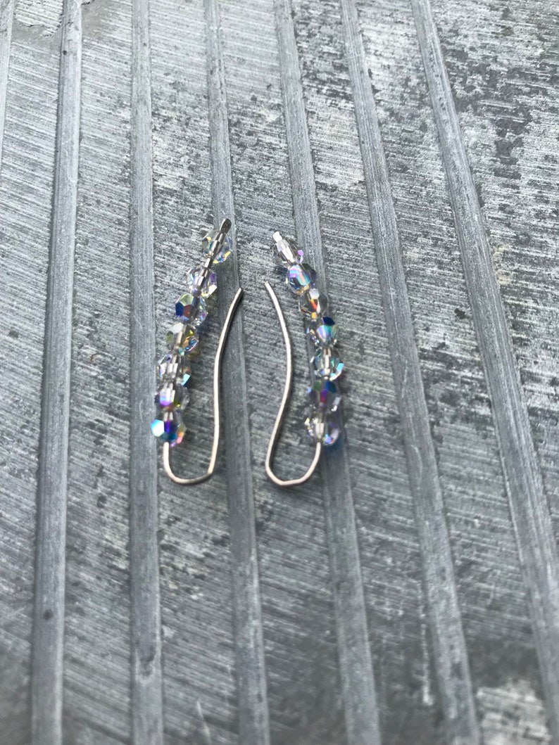 May include: A pair of silver earrings with a row of iridescent crystal beads hanging from each.