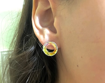 Op de afbeelding: Een paar ronde oorbel studs in iriserende gele en heldere kleur. De oorbellen zijn gemaakt van glas en hebben een facetgeslepen ontwerp.