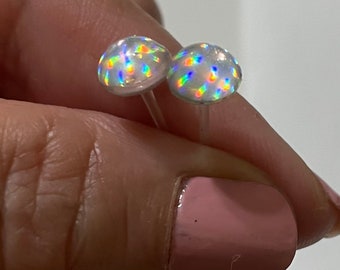 Op de afbeelding: Een paar iriserende oorbel studs met een witte achtergrond. De oorbellen zijn klein en rond en hebben een regenboogachtige glans.