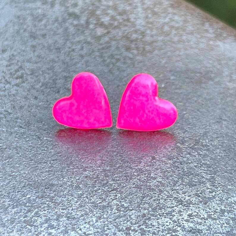 May include: A pair of pink heart-shaped stud earrings.