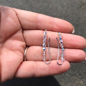 May include: A pair of silver earrings with clear iridescent crystal beads.