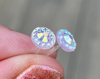 Op de afbeelding: Een paar doorschijnende oorbel studs met een iriserende glans en een zilveren achterkant.