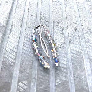 May include: A pair of silver earrings with clear crystal beads. The earrings are simple and elegant, and would be a great addition to any jewelry collection.