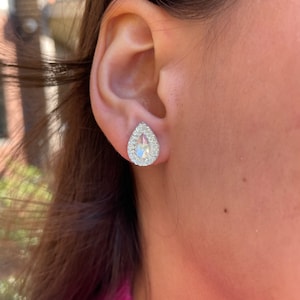 May include: A pair of silver teardrop-shaped earrings with clear crystal accents.