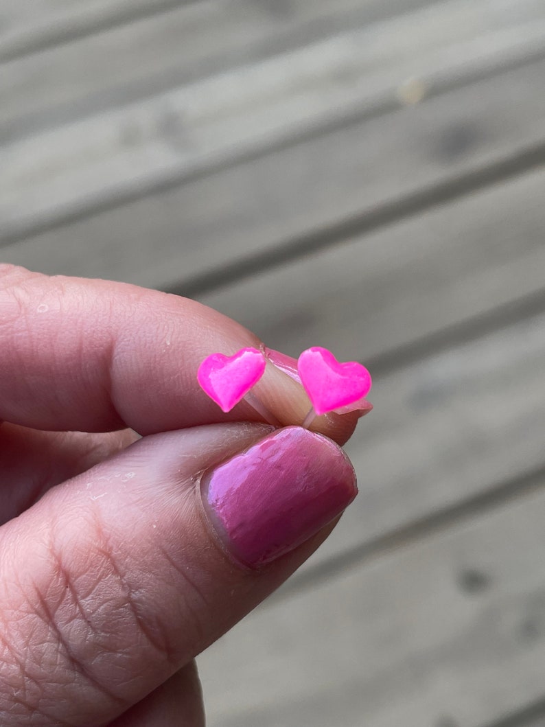 Puede incluir: Un par de pendientes de coraz&oacute;n rosa. Los pendientes son peque&ntilde;os y delicados, y son perfectos para a&ntilde;adir un toque de fantas&iacute;a a cualquier atuendo.