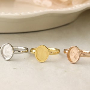 May include: Three oval-shaped ring blanks in silver, gold, and rose gold. The rings are made of metal and have a smooth finish.
