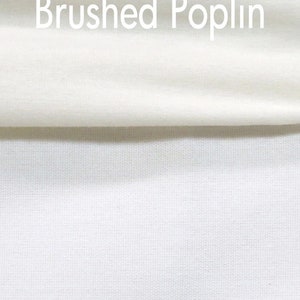 May include: Close-up of white fabric with the text "Brushed Poplin" in the upper portion of the image. The fabric is folded over, revealing a textured weave. The color is a bright, clean white.