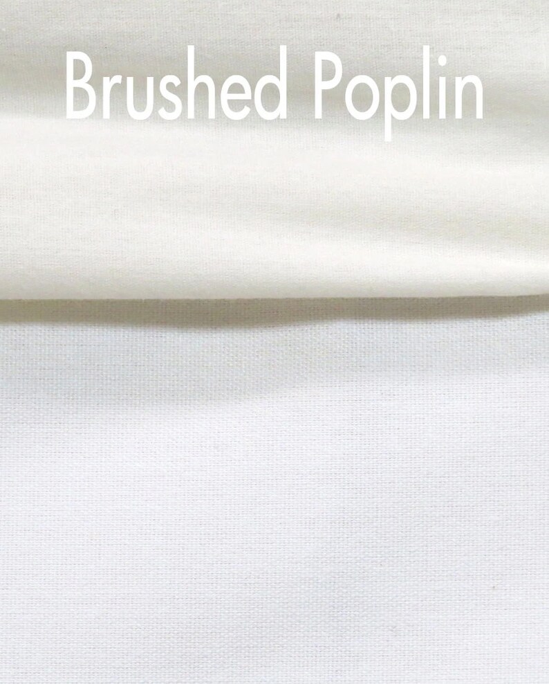 May include: Close-up of white fabric with the text "Brushed Poplin" in the upper portion of the image. The fabric is folded over, revealing a textured weave. The color is a bright, clean white.