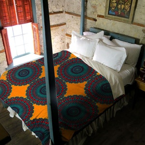 May include: A bed with a vibrant orange, teal, and red patterned comforter. The bed has a white bed skirt and is framed by a blue canopy. White pillows and a painting hang above the bed. The room has a rustic feel with a window and wooden shutters.