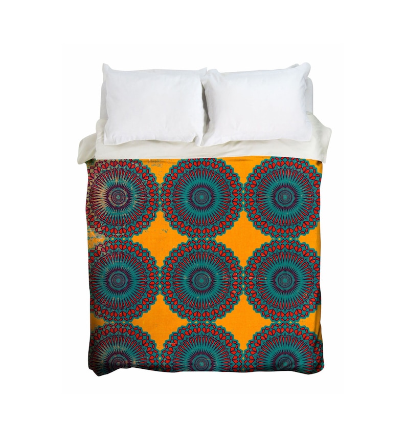 May include: A bed with white pillows and a duvet cover featuring a repeating mandala pattern. The mandala design has teal, red, and purple accents on a yellow background. The bedding is neatly arranged.