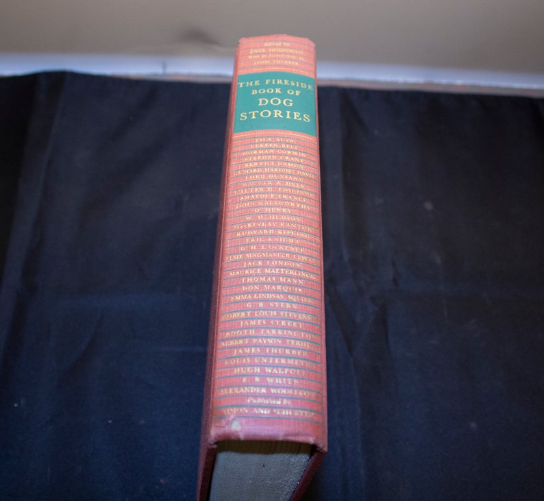 May include: The Fireside Book of Dog Stories, a red hardcover book with a green spine listing the authors of the stories included. The authors include Jack London, Thomas Mann, and more.