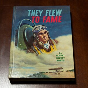May include: A vintage book cover with a blue background and the title "They Flew To Fame" in white and red lettering. The cover features a pilot wearing a leather helmet and goggles, sitting in a cockpit. The text "by Robert Sidney Bowen" is printed in green at the bottom of the cover.