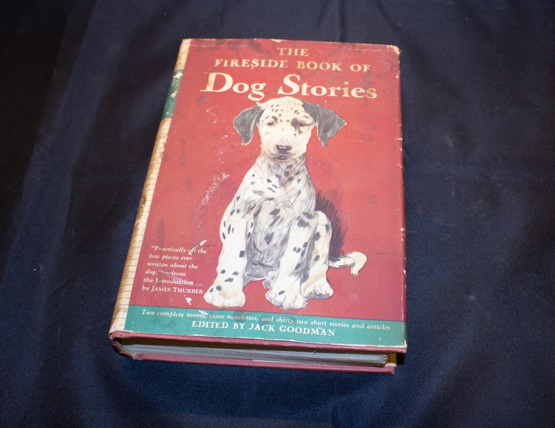 May include: The Fireside Book of Dog Stories, a red hardcover book with a black and white illustration of a Dalmatian puppy on the front cover. The book title is in white text and the author's name is in black text.