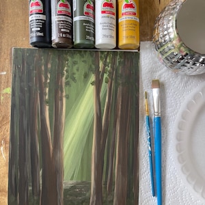 May include: An acrylic painting of a forest scene with tall trees and sunlight. The painting is accompanied by paint bottles in black, brown, green, white, and gold, along with paintbrushes, a palette, and a decorative pot. The paint bottles are labeled with the brand "Apple Barrel".