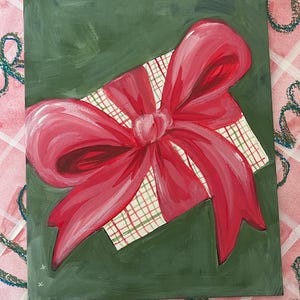 May include: A green canvas painting of a red and white plaid gift box with a large red bow on top.