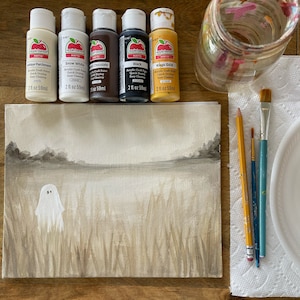 May include: A white canvas with a ghost painted on it, surrounded by brown and beige brushstrokes. Five bottles of acrylic craft paint in the colors antique parchment, snow white, chocolate, black, and kings gold are arranged in a row above the canvas. The paint bottles are 2 fluid ounces each.