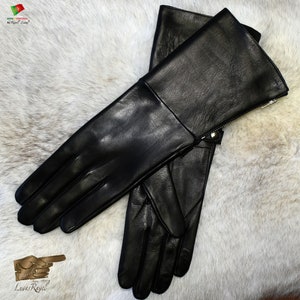 May include: A pair of black leather gloves with a zipper on the cuff. The gloves are laid out on a white furry surface.