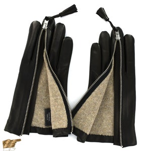 May include: Black leather gloves with a zipper detail and a brown wool lining. The gloves have a tassel on each wrist.