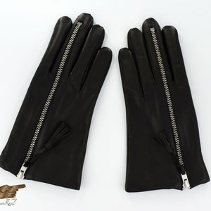 May include: A pair of black leather gloves with a zipper down the back of each glove. The gloves have a small tassel on the zipper pull.