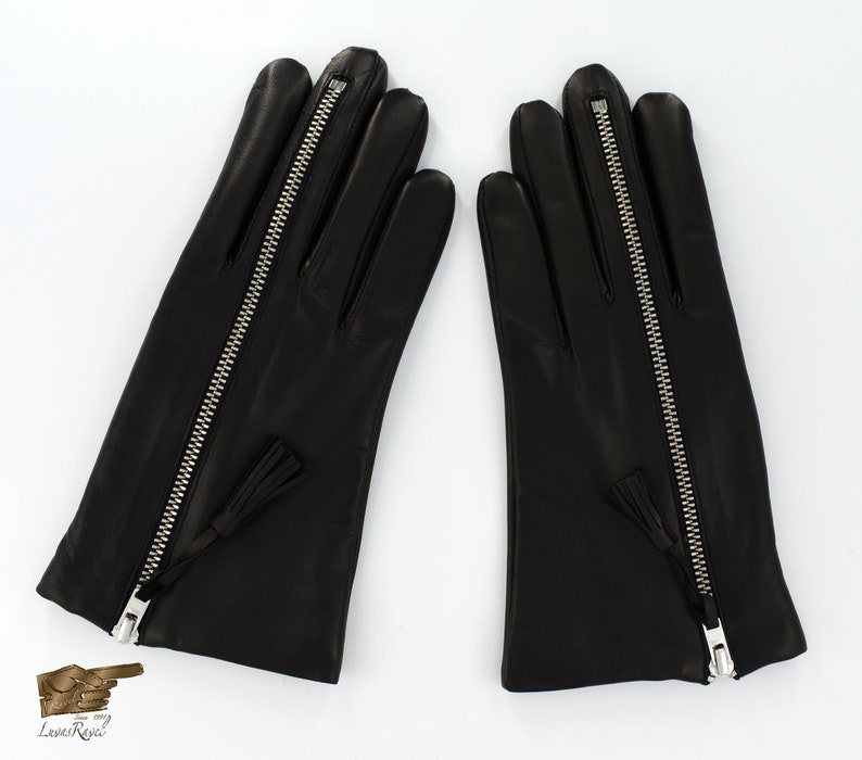 May include: A pair of black leather gloves with a zipper down the back of each glove. The gloves have a small tassel on the zipper pull.